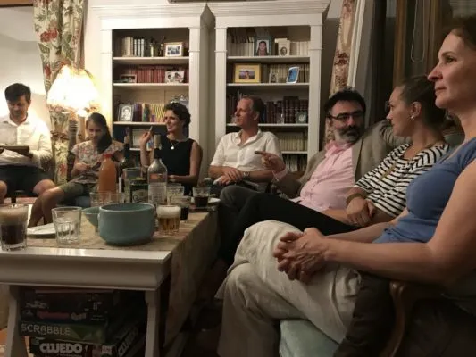 Adulți și tineri într-un salon, în discuție, seara.